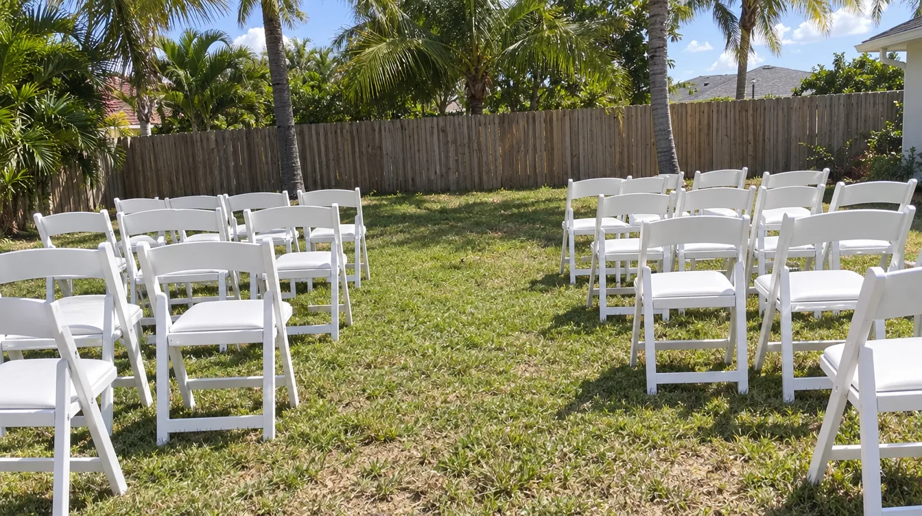 Rows of white padded resin chairs set up for a backyard wedding ceremony in Miami